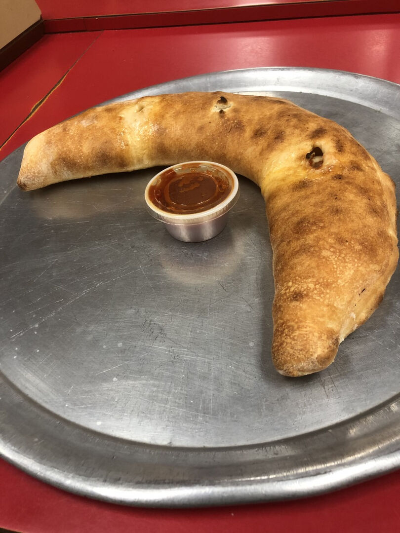 Fresh baked calzone with marinara dipping sauce from Schianos